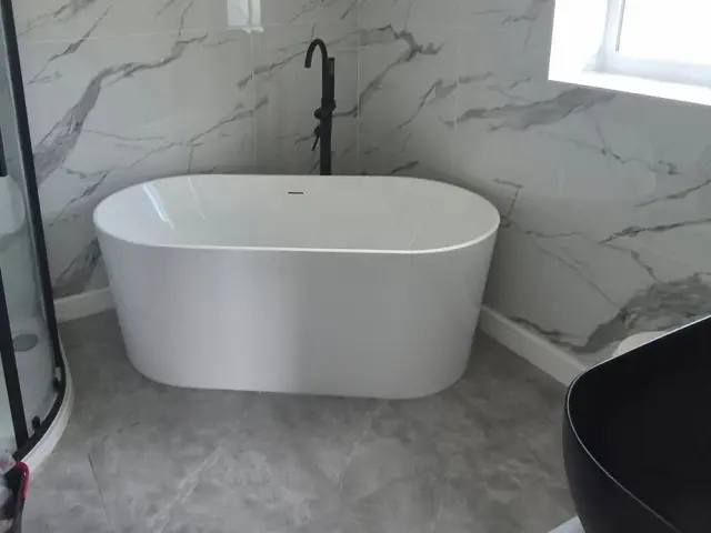 Freestanding bath and black framed shower in a marble-effect bathroom