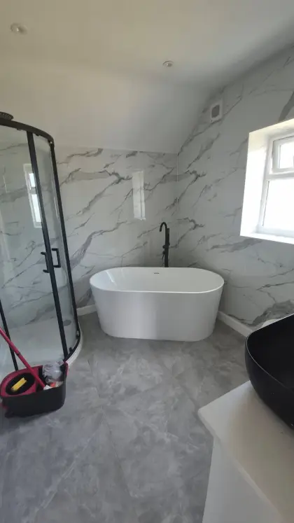 Freestanding bath and black framed shower in a marble-effect bathroom