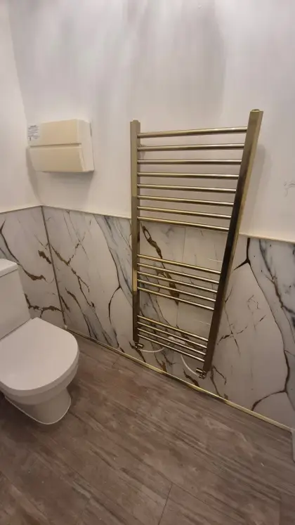 Tall brass towel rail and toilet