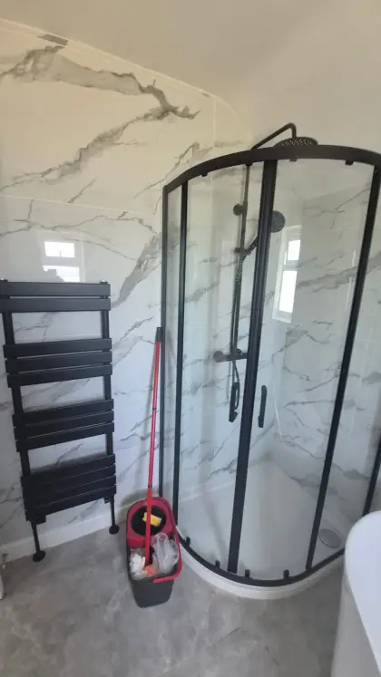 Black quadrant shower enclosure with matching towel radiator