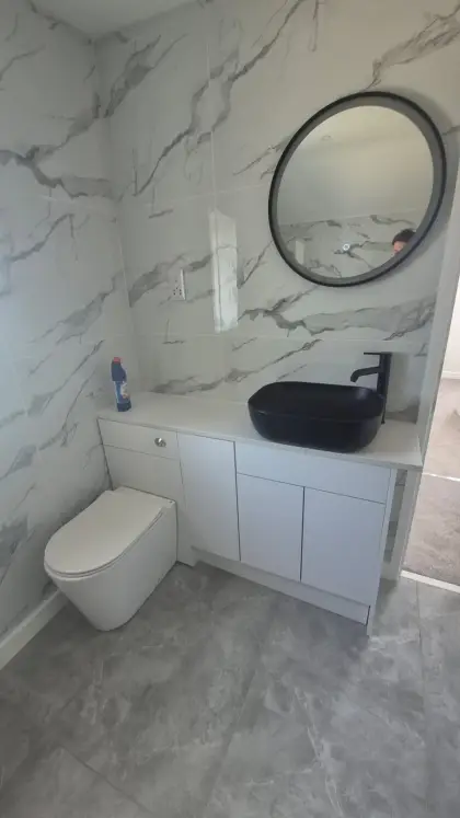 Vanity unit with black vessel basin and round mirror